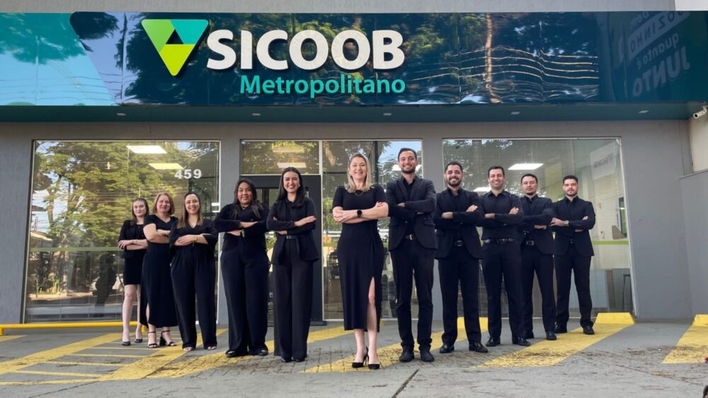 Grupo de gerentes do Sicoob Metropolitano reunido em frente a um dos postos de atendimento.